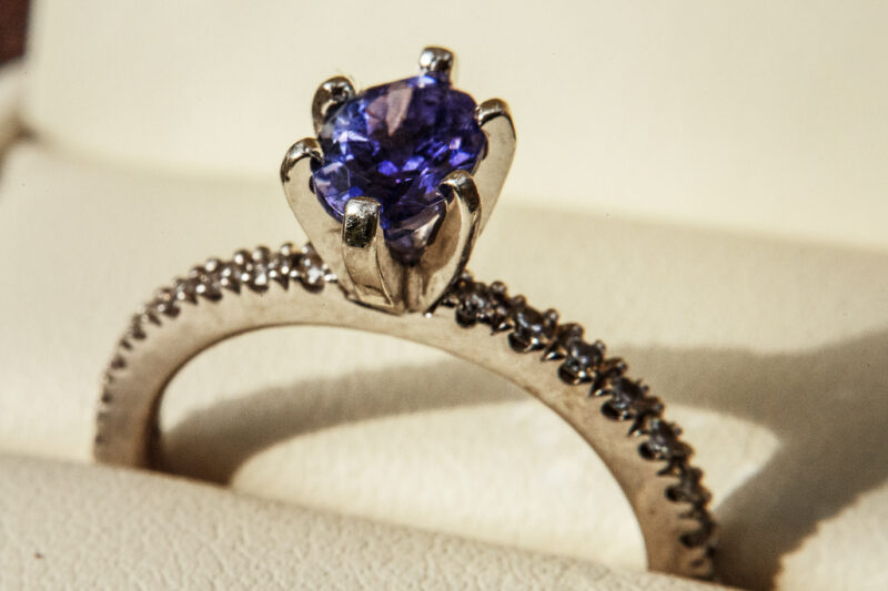 Egagement ring with blue precious stone on white pillow